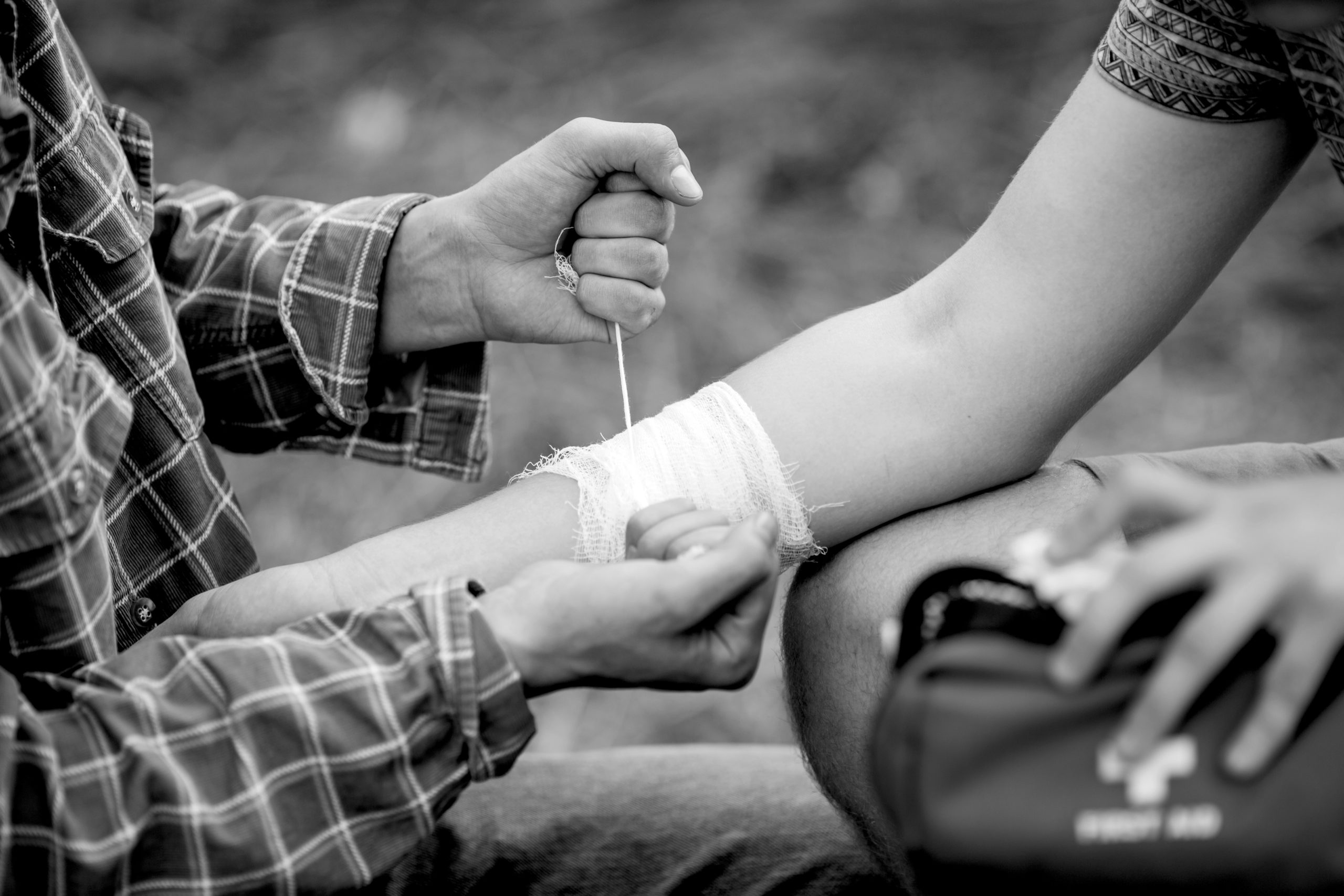 A person wrapping his friends injured arm in gauze