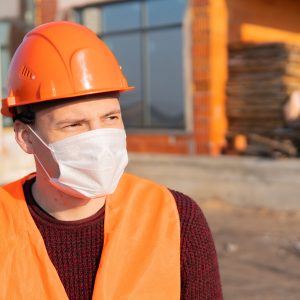 Portrait of male construction worker in medical mask and overalls